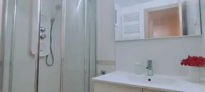 a white bathroom with a shower and a sink at Maria House. in Viladecáns