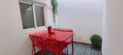 a red table and chairs on a balcony with a window at Maria House. in Viladecáns