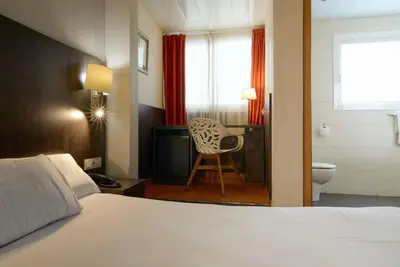 a bedroom with a bed and a television and a chair at Hotel Miramar Badalona in Badalona