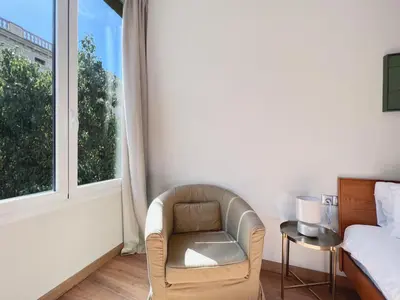 a bedroom with a chair and a bed and a window at Stay U-nique Apartments Fontanella in Barcelona