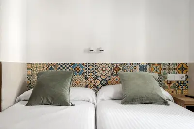 a bedroom with two beds and a wall with tiles at Hostal Baler in Barcelona