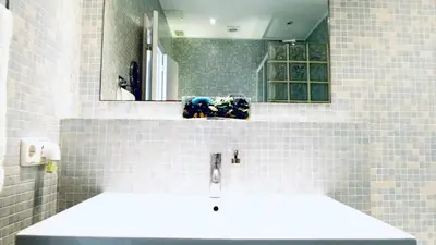 a white tiled bathroom with two sinks and a mirror at Enric Granados 17 in Barcelona