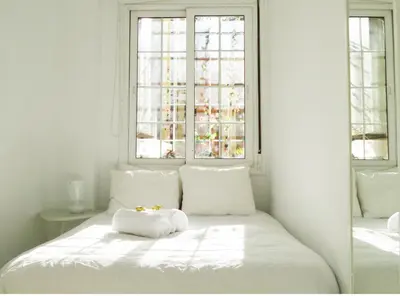 a white bed with white pillows and a window at Enric Granados 17 in Barcelona