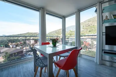 a dining room with a table and chairs and large windows at Apartamento Reisol in Castelldefels