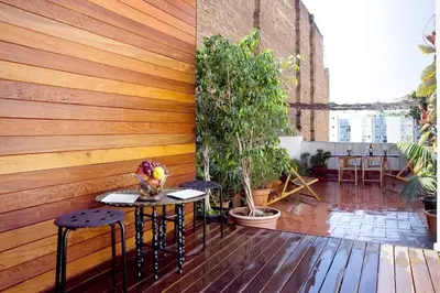 a patio with a wooden wall and tables and plants at Best deal PENTHOUSE! in Barcelona