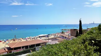 a beach with umbrellas and people in the water at Bianca Seaview & Beach Apartment in Montgat