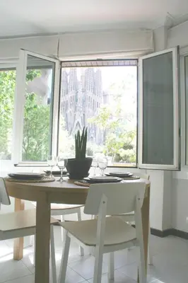 a dining room with a table and two windows at Apartment Carrer Lepant in Barcelona