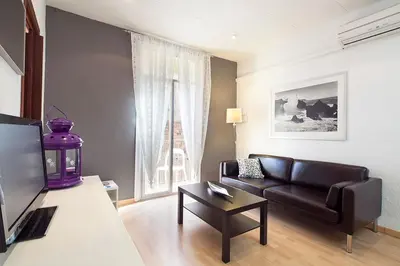 a living room with a black leather couch and a table at Deep Purple in Barcelona