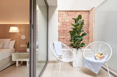 a living room with two white chairs and a bed at Hotel Omnium in Barcelona