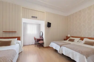 a hotel room with two beds and a desk at Hostal Oliva in Barcelona