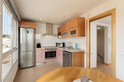 a kitchen with wooden cabinets and stainless steel appliances at Sitges Group Soul in Sitges