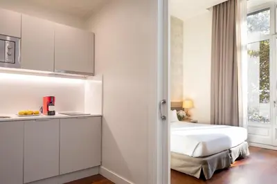 a white bedroom with a bed and a window at Duquesa Suites Landmark Hotel by Grup Duquessa in Barcelona