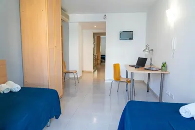 a room with two beds and a table with a laptop at Apartaments Turístics Residencia Vila Nova in Vilanova i la Geltrú