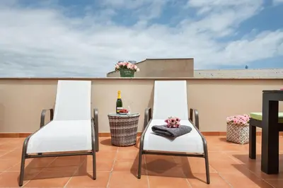 two white chairs on a patio with a bottle of wine at Matarolux 5 in Mataró