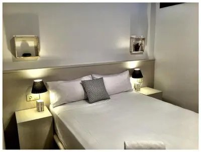 a bedroom with a white bed with two lights on it at Casas Apartamentos Gracia in Barcelona