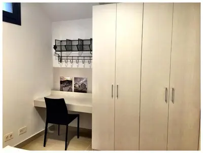 a white kitchen with a desk and a black chair at Casas Apartamentos Gracia in Barcelona