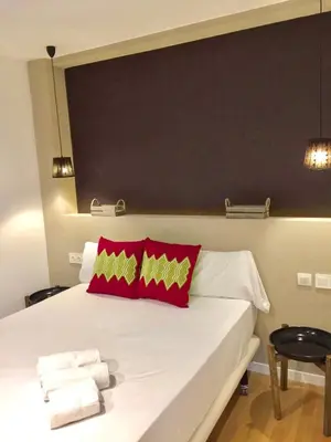 a bedroom with a white bed with red pillows at Casas Apartamentos Gracia in Barcelona