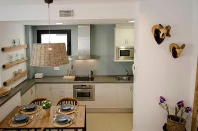 a kitchen with white cabinets and a wooden table at Casas Apartamentos Gracia in Barcelona