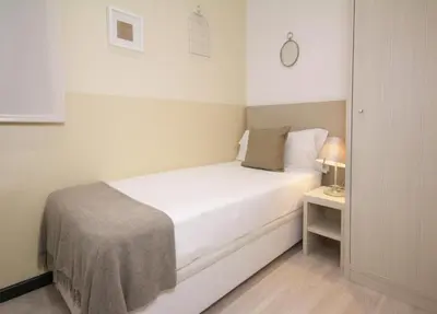a small white bedroom with a bed and a table at Suite Place Barcelona Còrsega in Barcelona