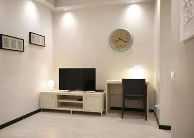 a room with a desk with a television and a clock at Suite Place Barcelona Còrsega in Barcelona