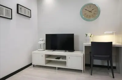 a living room with a tv and a chair and a clock at Suite Place Barcelona Còrsega in Barcelona