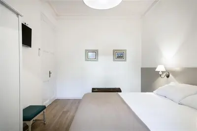 a white bedroom with a large bed and a chair at Apartment in downtown Barcelona - Vintage in Barcelona