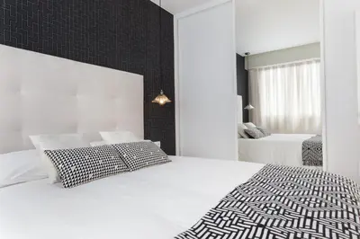 a white bedroom with two beds and a mirror at Passeig de Gracia Apartment in Barcelona
