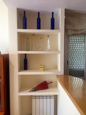a kitchen with white shelves with blue glass vases at Apartaments Villa Conchi in Sitges