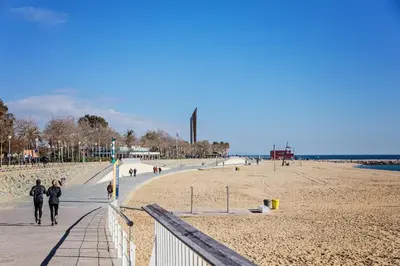 two people walking on the beach near the ocean at Sweett - Bogatell Beach in Barcelona