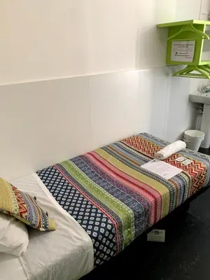 a bed with a quilt on it in a room at Central and Basic Universitat for YOUNG HOSTEL in Barcelona