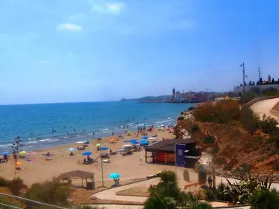 a beach with umbrellas and people on the beach at Apartment Aloha Sitges in Sitges
