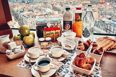 a table topped with cups of coffee and breakfast food at Enjoybcn Tapies Apartment in Barcelona