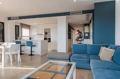 a living room with a blue couch and a kitchen at Enjoybcn Marina Apartment in Barcelona