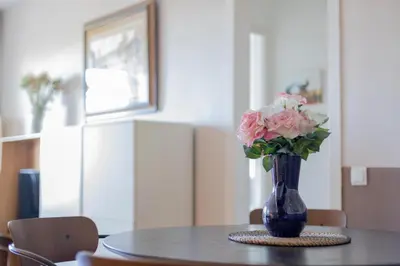 a blue vase with pink flowers sitting on a table at Housalia Guell Gaudi in Barcelona