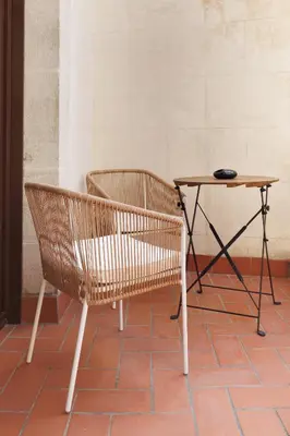 a table and a rattan chair next to a table and a table at Hotel La Pau in Barcelona