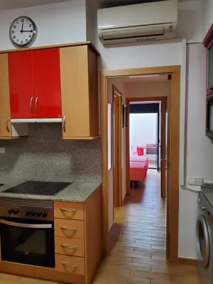 a kitchen with red cabinets and a clock on the wall at Apartment Sant Sebastià in Sitges