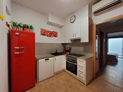 a kitchen with a red refrigerator and white cabinets at Apartment Sant Sebastià in Sitges