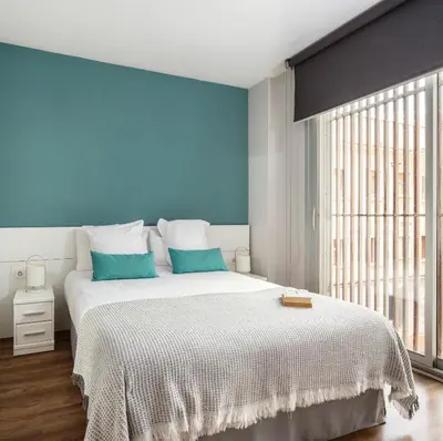 a bedroom with a large white bed with blue walls at Feelathome Poblenou Beach Apartments in Barcelona