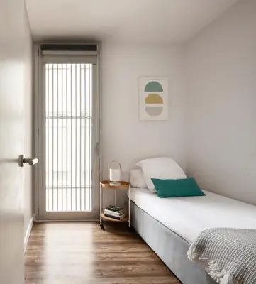 a white bedroom with a bed and a window at Feelathome Poblenou Beach Apartments in Barcelona