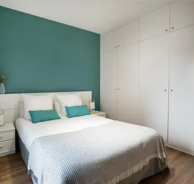 a bedroom with a white bed and a blue wall at Feelathome Poblenou Beach Apartments in Barcelona