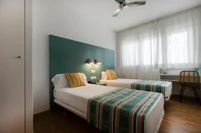 a hotel room with two beds and a green wall at Yomo Hostal BCN Port in Barcelona