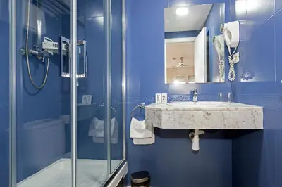 a blue bathroom with a sink and a shower at Yomo Hostal BCN Port in Barcelona