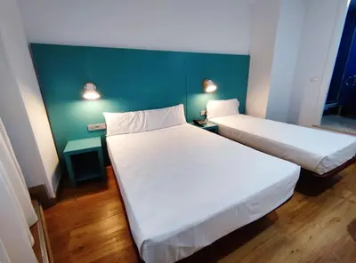 a room with two beds and a green wall at Yomo Hostal BCN Port in Barcelona