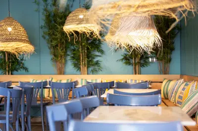 a restaurant with blue chairs and tables and chandeliers at Yomo Hostal BCN Port in Barcelona