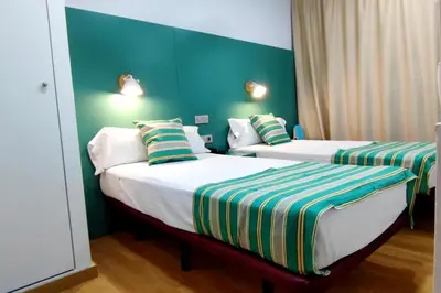 two beds in a hotel room with green walls at Yomo Hostal BCN Port in Barcelona