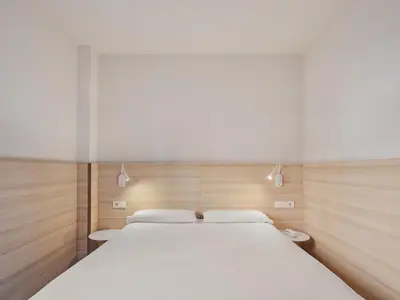 a bedroom with a large white bed with wooden walls at Hostal Lami in Esplugues de Llobregat