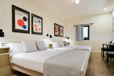 a hotel room with two beds and a desk at Hotel El Call in Barcelona
