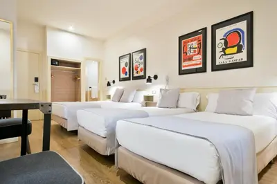 a hotel room with four beds and a table at Hotel El Call in Barcelona