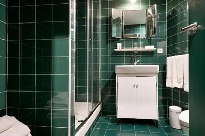 a green tiled bathroom with a toilet and a sink at Hotel El Call in Barcelona