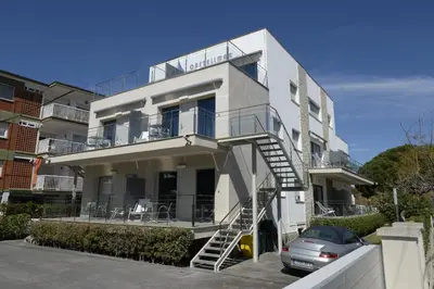 a white building with a balcony and a car at Apartamentos Castellmar in Castelldefels